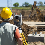 Surveyor working on construction site.